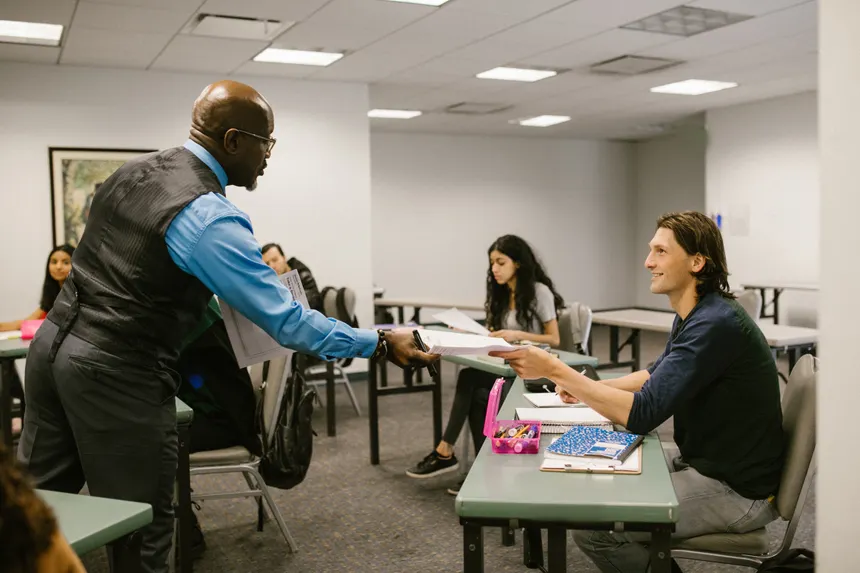 A teacher engaging with students in a university classroom, promoting active learning.