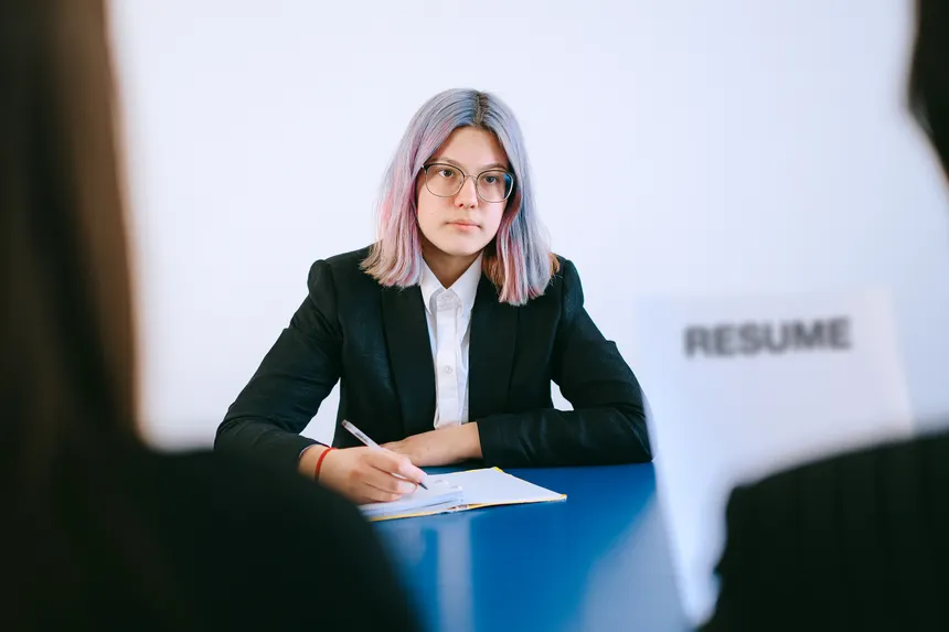 A young woman in a suit during a job interview, writing notes.