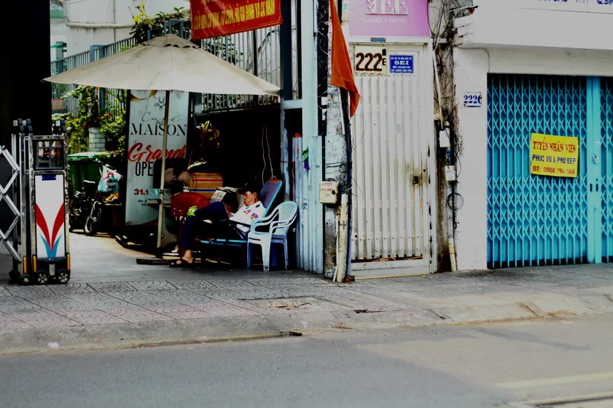A peaceful scene in Saigon with people lounging near a street vendor, surrounded by urban life.