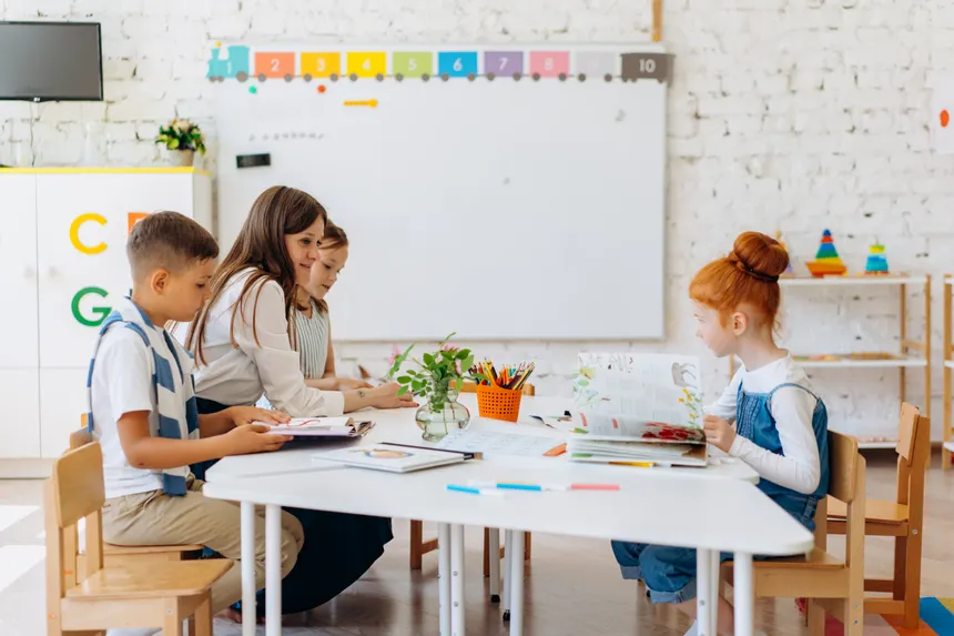 Students and teacher interacting in a bright, colorful classroom setting.