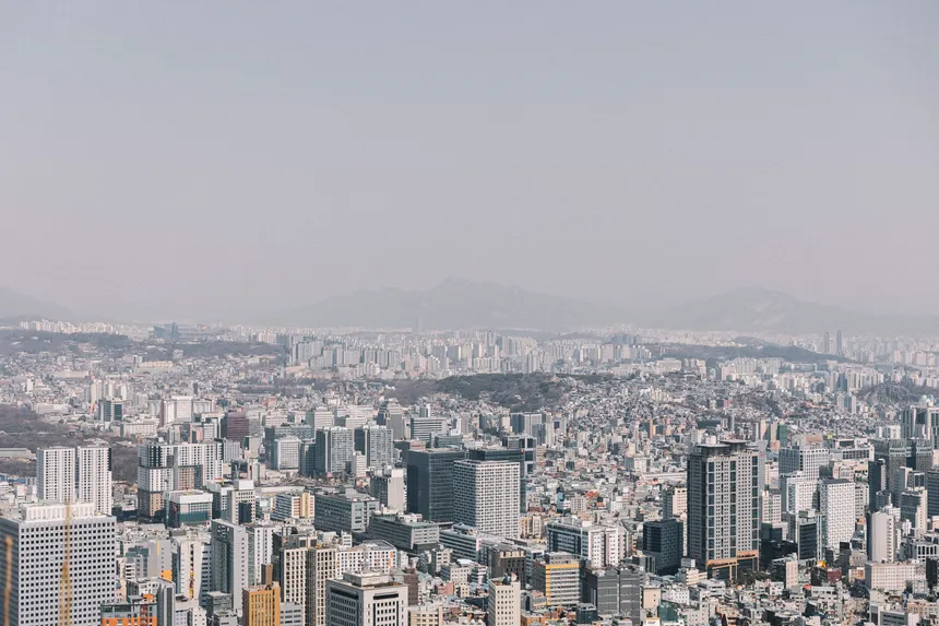 An expansive view of a city's skyline under a cloudy sky, showcasing modern architecture and urban density.